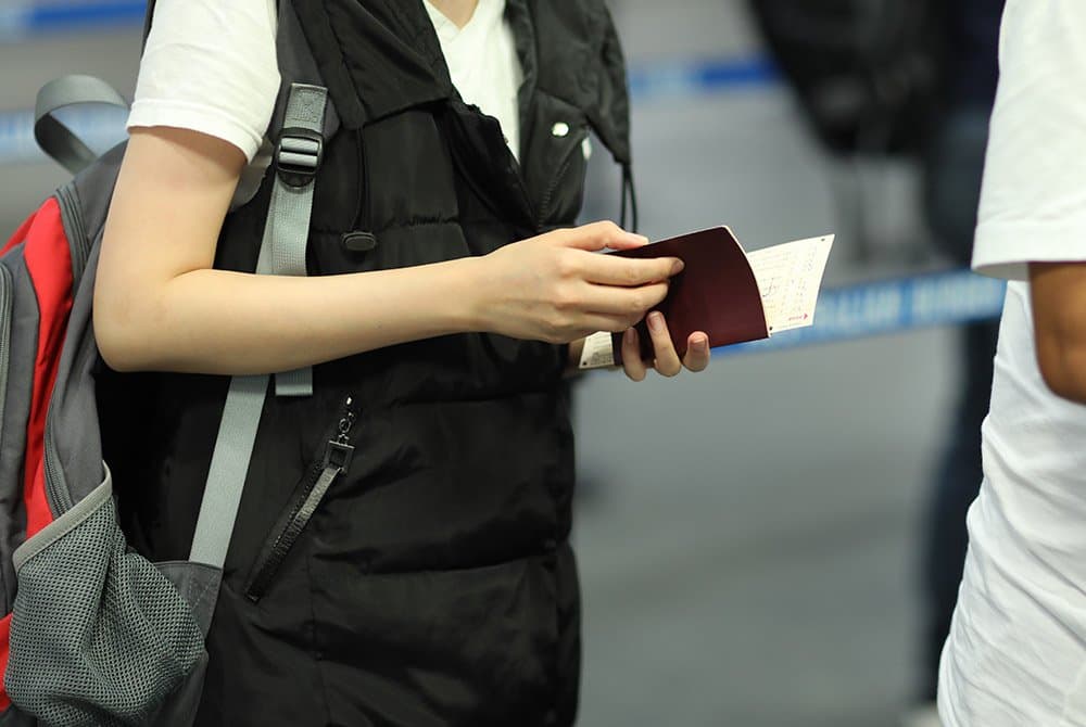 A traveller holds a passport and boarding documents at an airport.